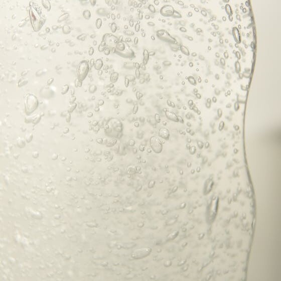 Glass jar with water with bubbles against white background