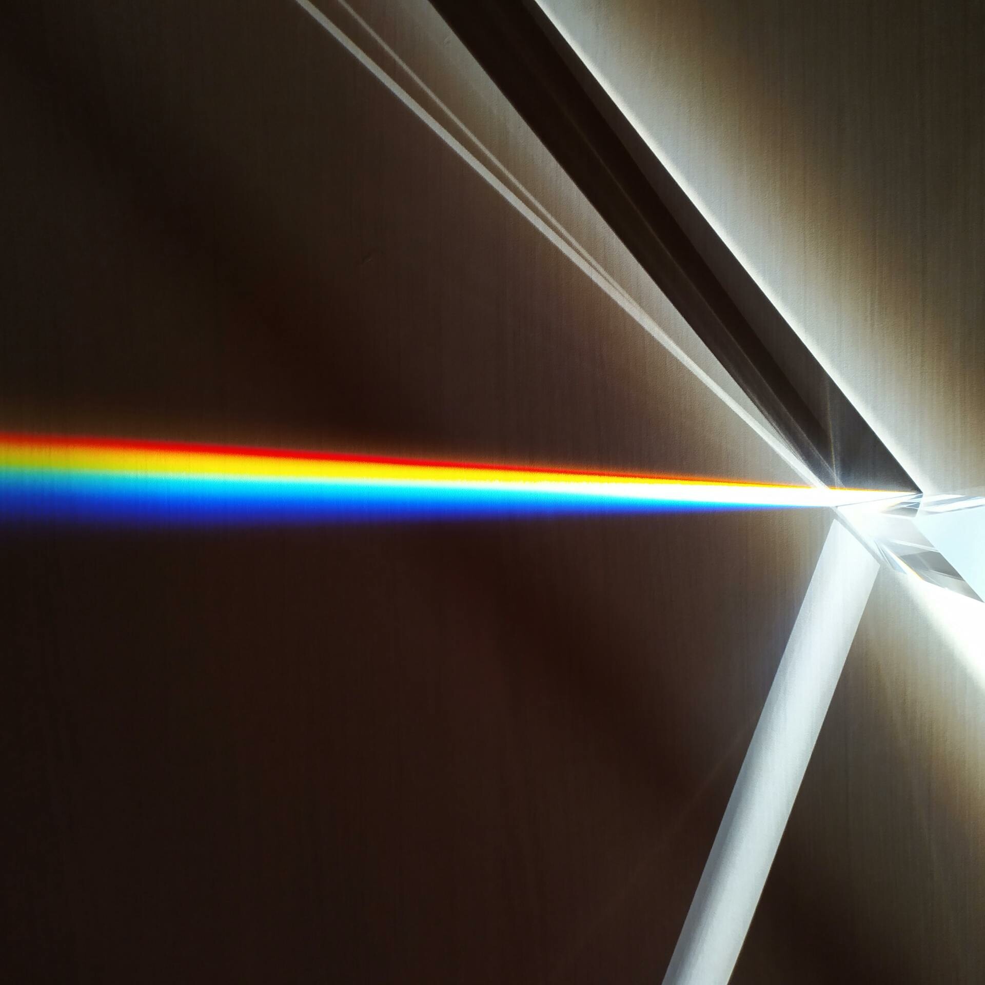 A colorful spectrum of light refracted through a glass prism creating a rainbow effect.